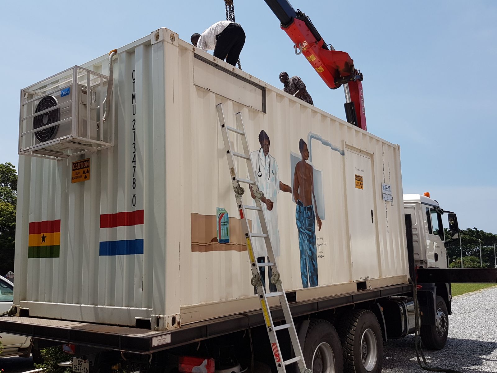 A Delft Imaging Ghana engineer performing maintenance on a mobile clinic container unit mounted on a truck.