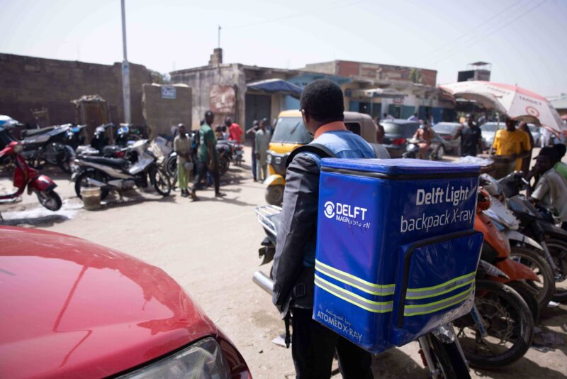 A man wears the Delft Light backpack and walks in the Nigeria urban settings