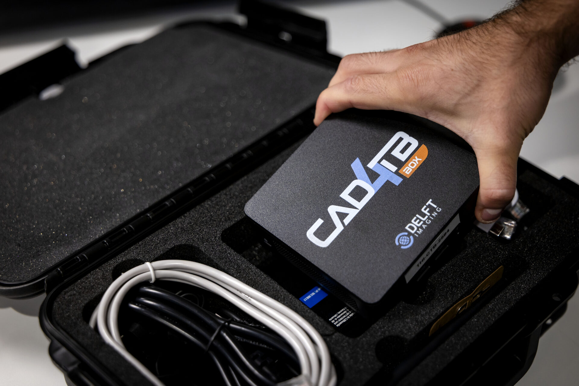 A hand picks the CAD4TB box out of the suitcase